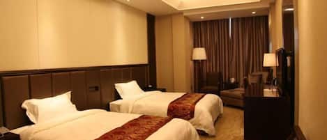 Habitación de hotel con dos camas, un escritorio, una silla y un ventanal con cortinas.
