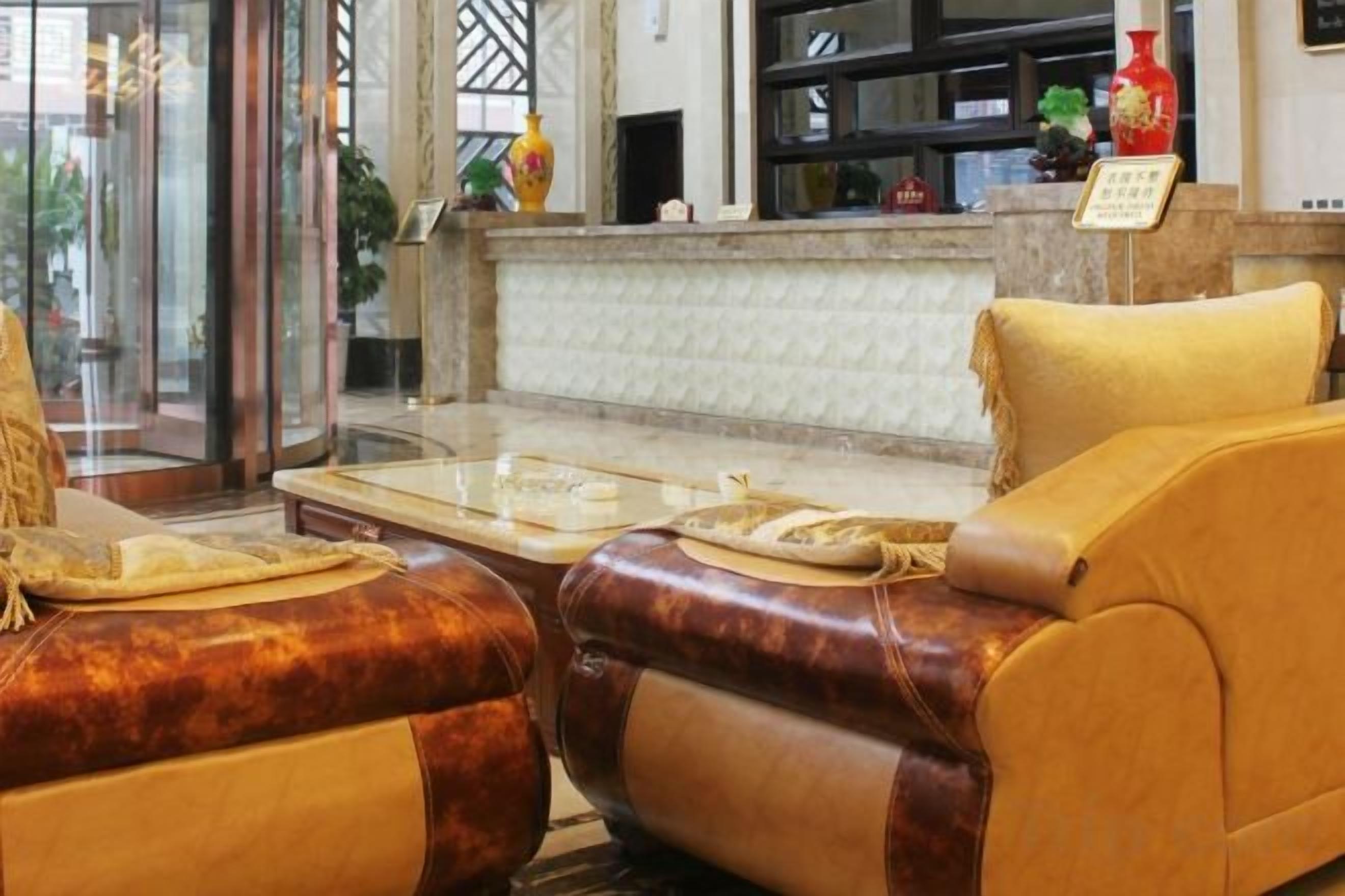 A lobby with a reception desk, a seating area with leather sofas, and a marble reception counter.