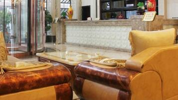 A lobby with a reception desk, a seating area with leather sofas, and a marble reception counter.