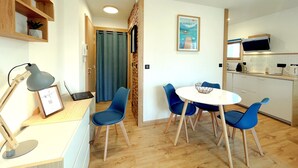 Una cocina moderna con comedor, armarios de madera, un televisor y un cuadro en la pared.