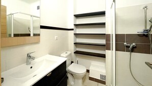 Un baño moderno con lavamanos, inodoro y ducha.