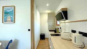 Una cocina moderna con encimeras de madera, horno empotrado y microondas. Hay un lavamanos pequeño y una ventana sobre él.