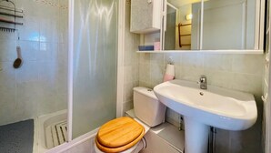 A bathroom with a shower, toilet, and sink.