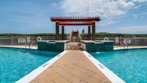 A swimming pool with a central walkway, surrounded by a fence, and a red canopy structure. - Pearl 1003 Sugar white sand and emerald waters (Navarre)