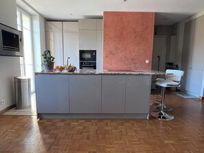 A modern kitchen with a central island, built-in appliances, and a bar stool.