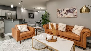 Een moderne woonkamer met een bruine leren bank, een witte marmeren salontafel en een wereldkaart als kunstwerk aan de muur.