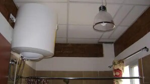 Ett badrum med dusch, handduksställ och en hängande lampa.