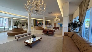 Eine geräumige Lobby mit einem großen Kronleuchter, bequemen Sitzgelegenheiten und einer Rezeption.