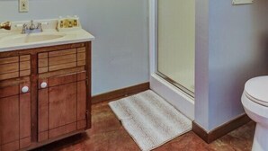 Een badkamer met een houten wastafelmeubel, een glazen douchecabine en een toilet.