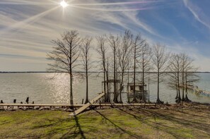 A lakeside view with a wooden dock, a small wooden structure, and leafless trees.