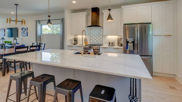 A modern kitchen with a large island, stainless steel appliances, and pendant lighting.