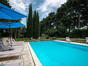 Relax by the serene pool surrounded by lush greenery and comfortable lounge chairs.