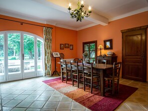 Enjoy meals in this dining area with a wooden table and chairs, surrounded by framed artwork and a chandelier.