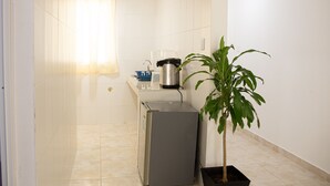Una cocina compacta con refrigerador, cafetera y una planta en maceta.