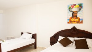 Habitación de hotel con dos camas individuales, una mesa redonda pequeña y un cuadro en la pared.