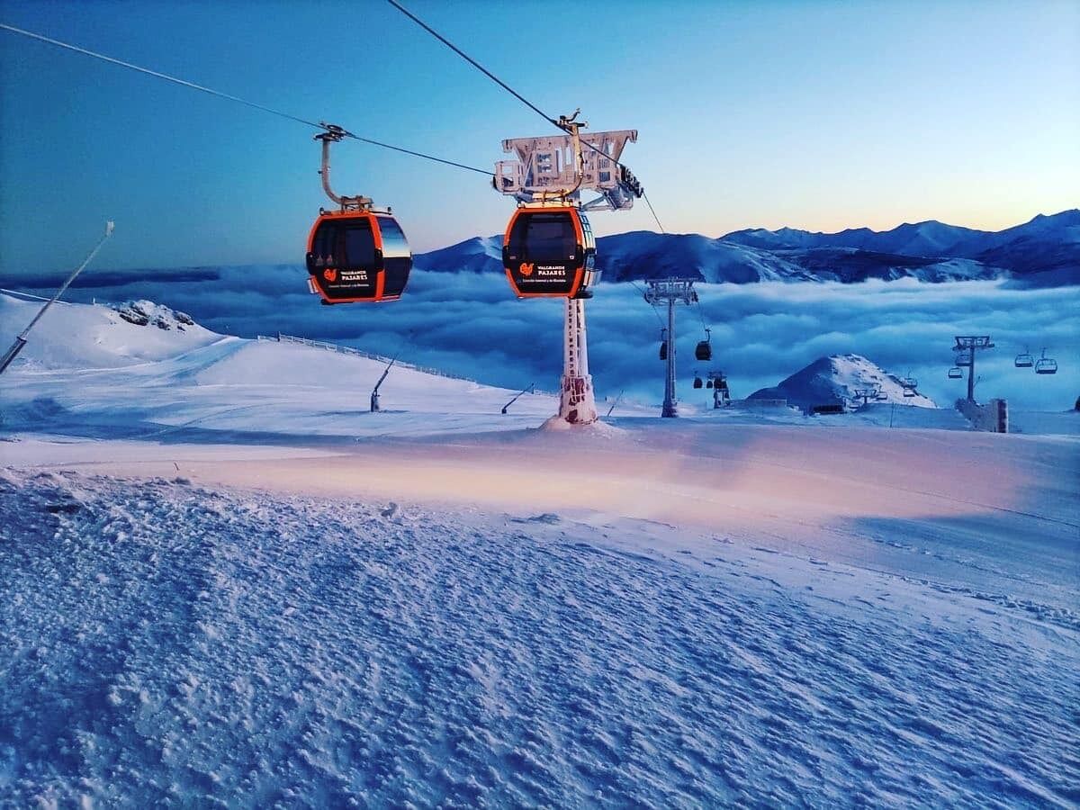 Eine Seilbahn mit zwei Kabinen, ein Sessellift und eine verschneite Berglandschaft.