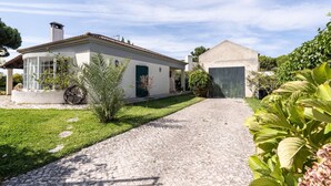 A house with a cobblestone driveway, a covered patio, and a garden with various plants. - Miro Villa, Meco, Sesimbra (Sesimbra)