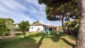 A white house with a tiled roof, surrounded by a grassy yard and trees. - Miro Villa, Meco, Sesimbra (Sesimbra)