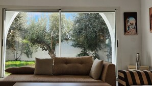 Un salón moderno con sofá, un ventanal grande y un cuadro en la pared.