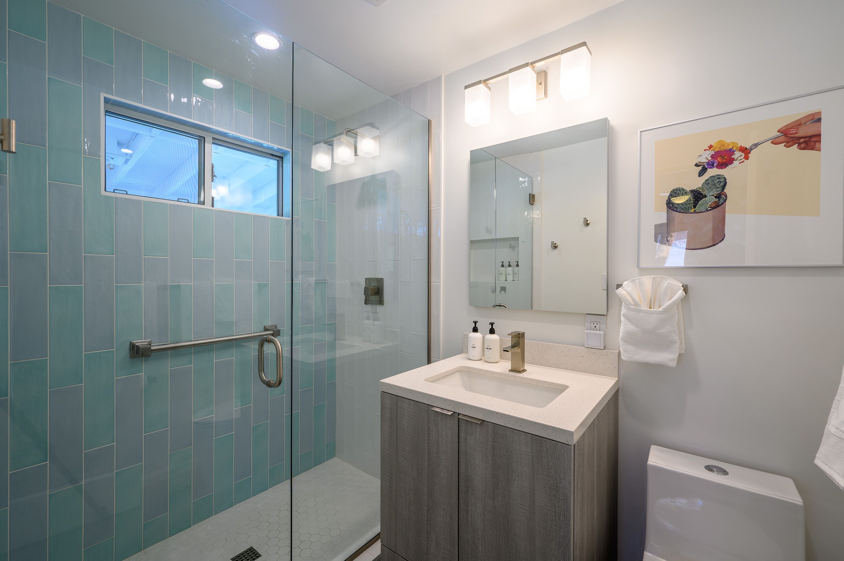 A modern bathroom with a glass shower enclosure, a vanity with a sink, and a large mirror.