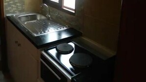 Una cocina compacta con un lavamanos, estufa y alacenas.