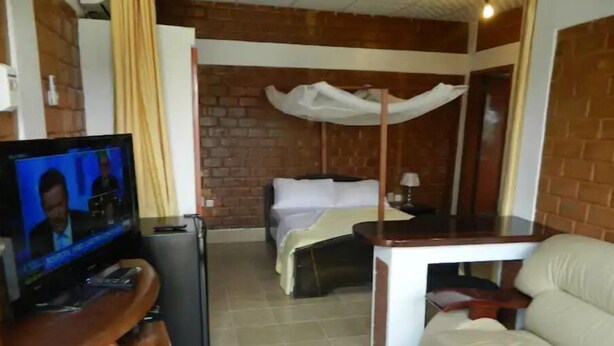 Una habitación de hotel compacta con televisión, cama, una pequeña mesa y un sofá.