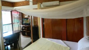 Una habitación con cama, escritorio, silla y aire acondicionado.