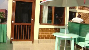 Un patio con mesa y sillas, una puerta de madera y una ventana con vistas.