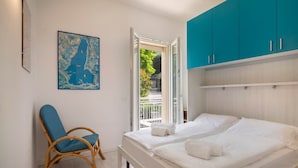 A bedroom with two beds, a blue chair, a map on the wall, and a view of the outside. - Villa Malù - APT Mara Pool and lake view (Torri del Benaco)