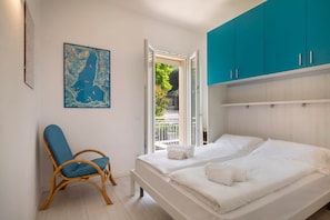 Quarto com duas camas, uma cadeira azul, um mapa na parede e vista para o exterior.