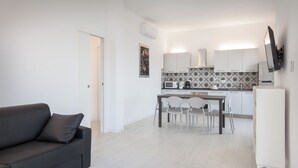 A modern kitchen with white cabinets, a tiled backsplash, and a dining area with a table and chairs. - Villa Malù - APT Mara Pool and lake view (Torri del Benaco)