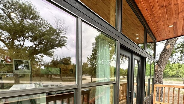 A modern building with large windows, a wooden deck, and a black doormat.
