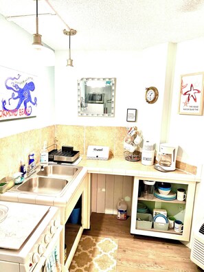 Una cocina con un lavamanos, estufa y varios utensilios.