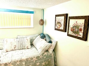 A room with a bed, a window with blinds, and two framed pictures on the wall. - Sandy Feet Retreat  - At Symphony Beach Club! (Ormond Beach)