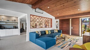 Un salon moderne avec un canapé d’angle bleu, une table basse et un plafond en bois.