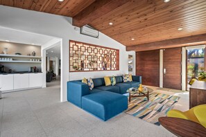 Un soggiorno moderno con un divano componibile blu, un tavolino da caffè e un soffitto in legno.
