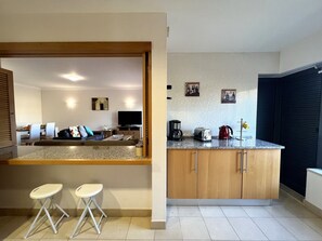 A modern kitchen with a countertop, cabinets, and a dining area with a sofa and chairs. - ALBUFEIRA MODERN 4 by HOMING (Albufeira)