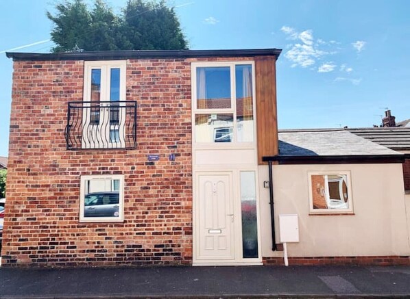 A two-story brick house with a white door, a small window, and a balcony. - Boutique Detached House in Uphill Lincoln (Lincoln)