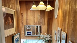 A wooden interior with a central counter, framed pictures, a mirror, and a hanging light fixture.