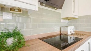 A modern kitchen with a built-in induction cooktop, white cabinets, and a backsplash of light-colored tiles. - Townhouse near to Castle, Cathedral and Bailgate (Lincoln)