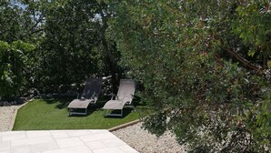 Un patio con dos sillones de descanso y un pequeño césped.