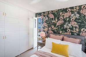 A bedroom with a bed, a nightstand, a lamp, and a wardrobe.