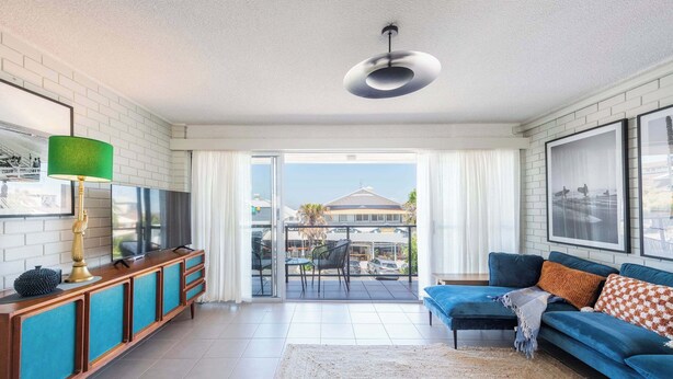 A modern living room with a sofa, TV, and a balcony with a view.