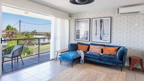 A living room with a blue sofa, a view of the outdoors, and a white brick wall.