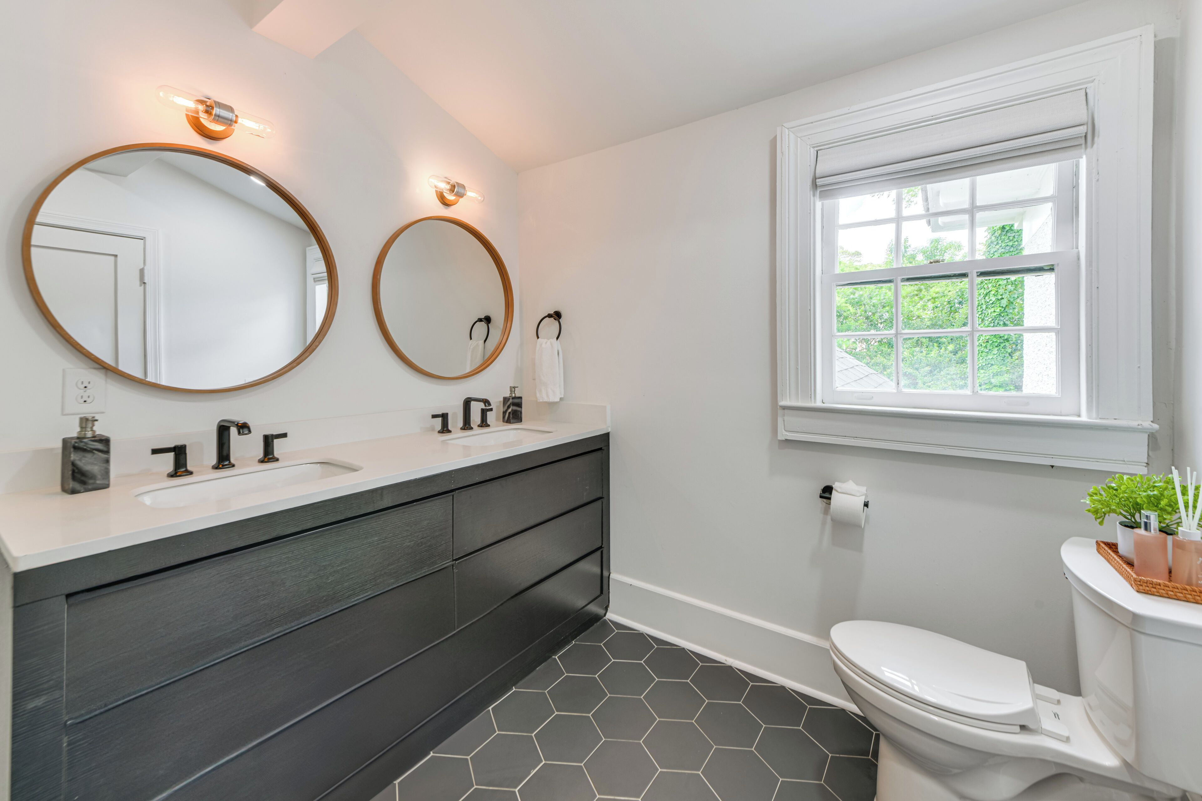 Une salle de bain moderne avec deux lavabos, des toilettes et une fenêtre.
