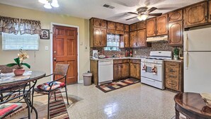 A kitchen with wooden cabinets, a white refrigerator, a stove, and a ceiling fan. - Family Home Near Panola Mountain State Park! (Stonecrest)