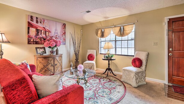 A living room with a red sofa, a glass coffee table, a beige armchair, and a patterned rug. - Family Home Near Panola Mountain State Park! (Stonecrest)