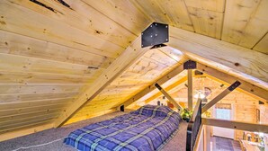 Een gezellig slaapkamer op zolder met een bed, houten balken en een raam.