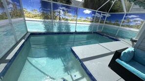 Une piscine avec vue sur les palmiers et une plage, entourée d’un espace couvert aménagé avec un canapé.