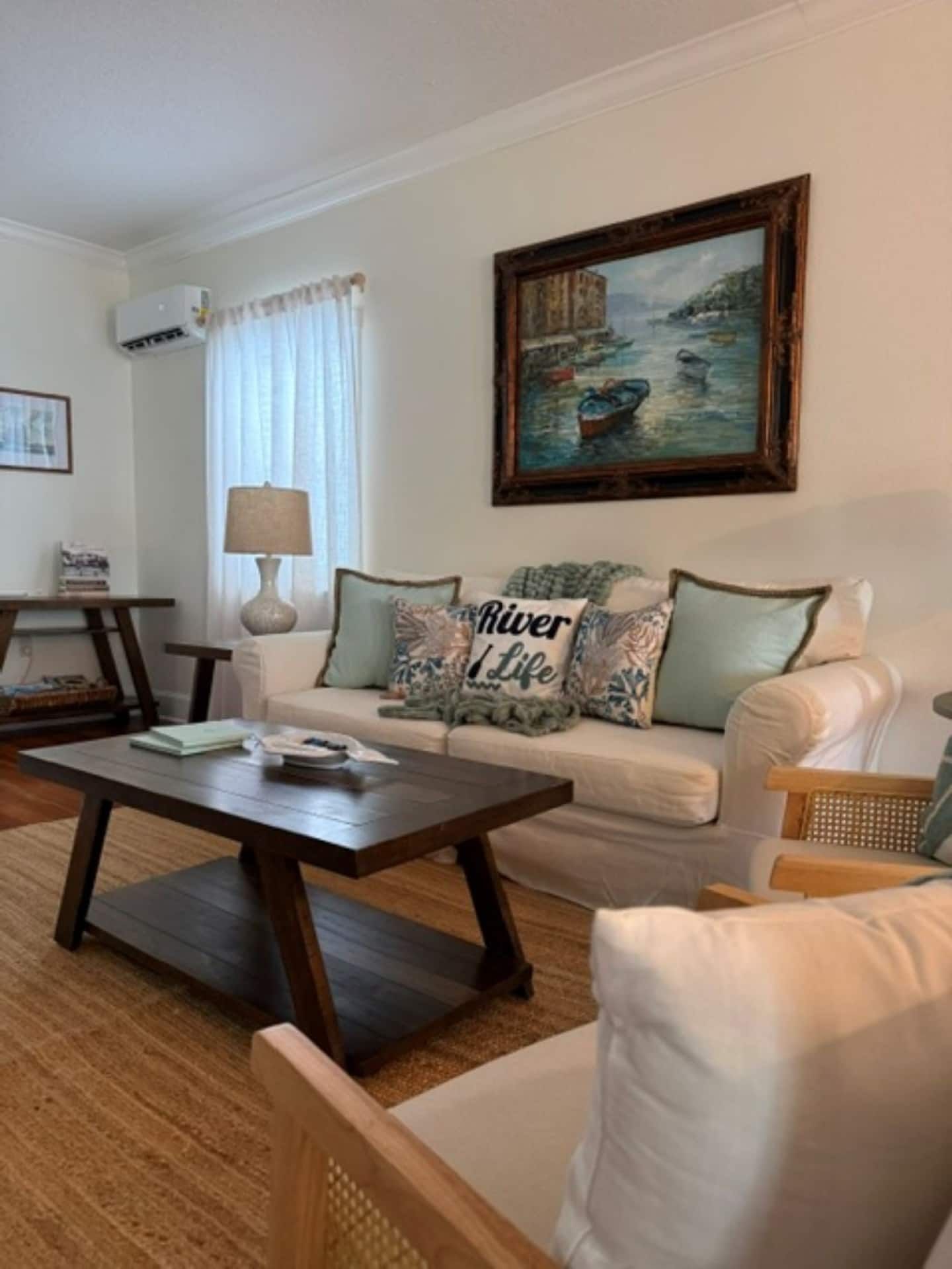 A living room with a sofa, a coffee table, a painting, and a lamp.